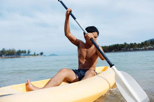 トロピカルビーチでカヤックを楽しむアドベンチュラスアジア人男性 — ストック写真