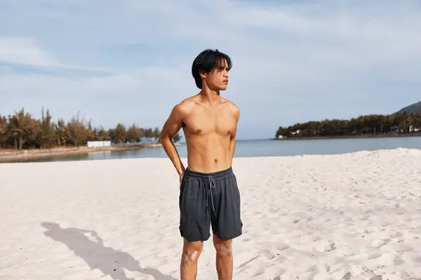 トロピカルアイランドビーチで夏休みを楽しむ筋肉質のアジア人男性 笑顔とシャツレスの水着でフィットボディを披露 — ストック写真