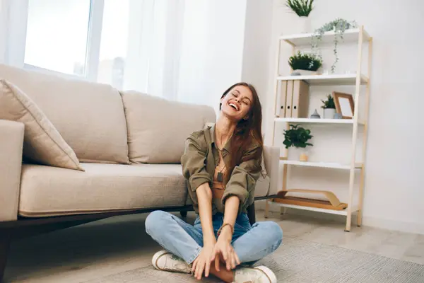 居心地の良いホームコンフォート 彼女の平和なリビングルームでモダンなソファーでリラックスする幸せな女性 — ストック写真
