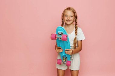 Neşeli küçük kaykaycı kız Pembe Penny sörf tahtasında şık bir yaz portresiyle