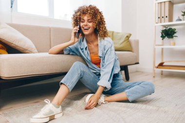 Konforlu Ev Gevşemesi: Kanepede Telefonu Tutan Kadın, Çevrimiçi Oyunlardan Hoşlanıyor ve Mutlu Okumalar