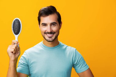 Güzel adam sakalını kaybeder, saçlarını tarar, saçlarını tarar, saçlarını tarar, saçlarını tarar, saçlarını tarar, berber sarısı arka plan tarar.