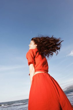 Güneşli sahilde Neşeyle Dans eden Gülümseyen Kadın Denizin Özgürlüğünün tadını çıkarıyor.