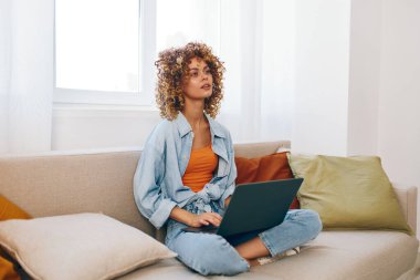 Oturma odasında dizüstü bilgisayarda çalışan gülümseyen kadın..