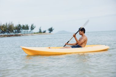 Mutlu Asyalı Adam Tropikal Sahilde Kano Macerasının tadını çıkarıyor