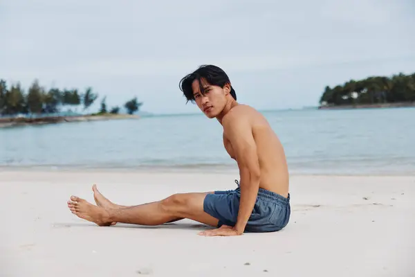 フィットネスライフスタイルでサンセットビーチランを楽しむ筋肉アジアの選手 — ストック写真