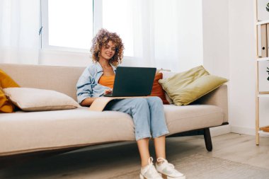 Oturma odasında dizüstü bilgisayarda gülümseyen kadın.