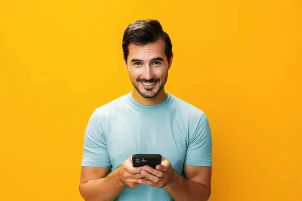 Mobile man phone cyberspace communication copy technology message smiling happy studio yellow business lifestyle eyeglass space surprise smartphone smile pointing phone toothy portrait