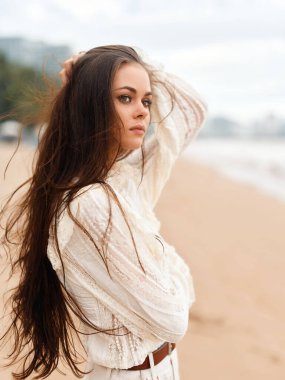 Serene Summer Beauty: A young Attractive Woman on a Outdoor on a White Sandy Beach by the calm cean, His Brunette hair Swing in the Wind, with a Stylish Bikini under the Sunny Blue Sky
