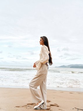 Zarif ve mutlu görünen zarif bir bayan, Sahil kenarındaki bir kafede tek başına oturuyor, Mavi Okyanus 'un rahatlatıcı yaz tatilinin tadını çıkarıyor.