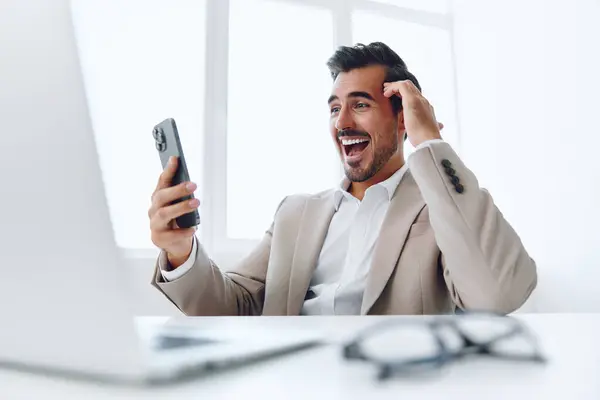Man worker happy success professional laptop conversation office person handsome phone corporate cellphone business winner smile young working computer occupation talk suit internet businessman