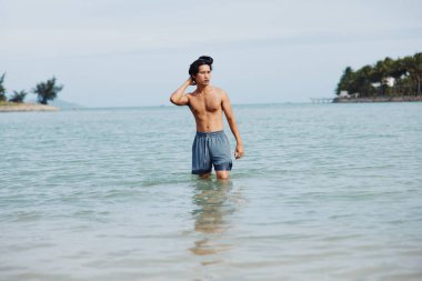 Gülümseyen Asyalı Adam Tropikal suda eğleniyor ve özgürlüğün tadını çıkarıyor