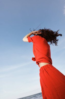 Neşeli Kadın Özgürlüğü Kucaklıyor, Güneşli Sahilde Dans Ediyor: Gülümseyen Yaz Eğlencesinin Canlı Portresi