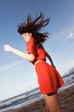 Denizde Neşeli Dans: Kızıl Sahilde Özgürlük ve Eğlenceyi Kucaklayan Gülümseyen Kadın