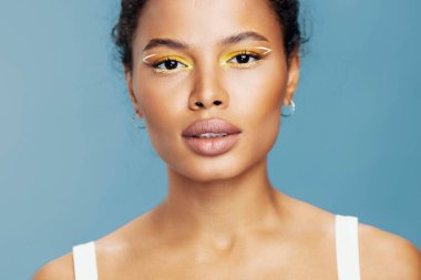 Cilt gülüşü, saç mutluluğu kıvırcık, yakın çekim, Afrikalı güzel Amerikan tenli fotoğraf stüdyosu, mavi stüdyo, mutlu yaşam tarzı, moda tarzı kadın makyajı.