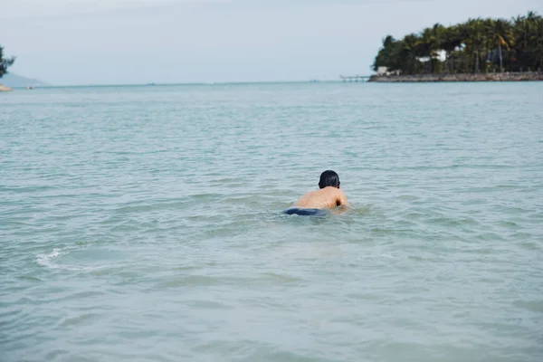 アクティブな夏休みを楽しんでいる笑顔のアジア人男性 熱帯ブルーの海水でスプラッシュして泳ぐ — ストック写真