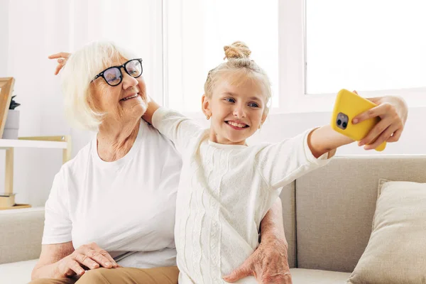 Two child hugging call t-shirt grandmother indoors sofa bonding smiling granddaughter space selfie togetherness white photography people family copy video phone education