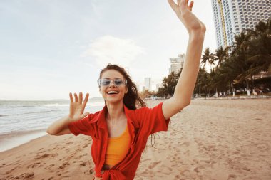 Gülümseyen Kadın Sahilde Renkli Günbatımının tadını çıkartıyor, Özgürlüğü ve Neşeyi Kucaklıyor