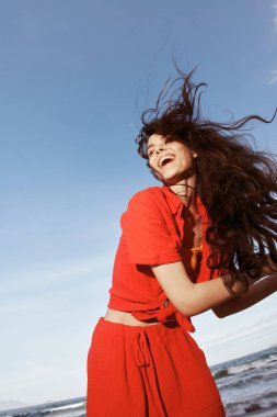 Neşeli kadın güneşli bir sahilde özgürlük ve mutlulukla dans ediyor.