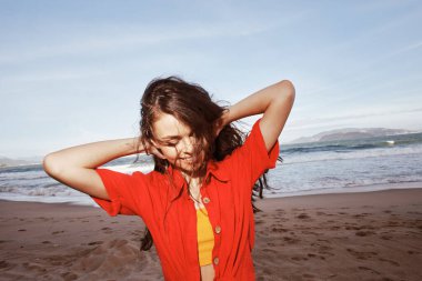 Neşeli, gülümseyen kadın Kumsal Tatilinde Kırmızı Giysilerle Özgürlüğün tadını çıkarıyor