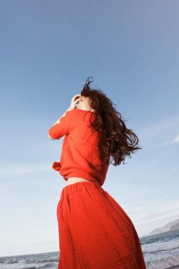 Güneşli bir sahilde Neşeyle Dans eden Gülümseyen Kadın, Özgürlük ve Eğlenceyi Kucaklayan