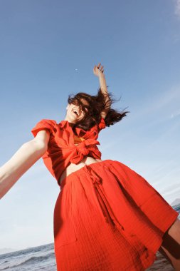 Yazın neşeli kucaklaması: Gülümseyen Kadın Güzel Sahilde Özgürlük ve Mutlulukla Dans Ediyor