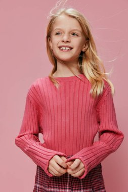 Neşeli İfadesi ve Stüdyonun Arkaplanı olan Pembe Giyimli Gülümseyen Okul Kızı