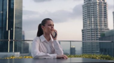 İş kadını cep telefonuyla şehrin arka planında ve gökdelenlerde konuşan, modern kentsel hayat tarzı serbest çalışan. Yüksek kalite 4k görüntü