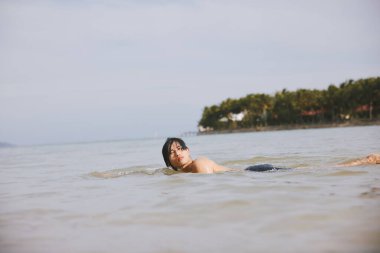 Neşeli Asyalı Adam Tropikal Plaj Tatilinde Aktif Su Sporunun keyfini çıkarıyor