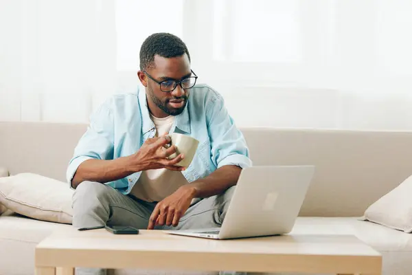 Усміхнений Афроамериканський Чоловік Працює Ноутбуці Розмовляє Телефону Затишному Домашньому Офісі — стокове фото