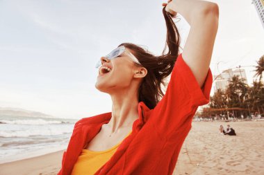 Renkli Özgürlük: Açık Ağızlı Gülümseyen Kadın, Gün Batımında Sahilde Moda Yaşam Tarzının Tadını Çıkarıyor