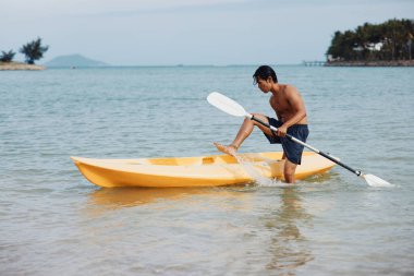 Yaz tatilinde Palm Trees ve Crystal Clear Water ile Tropikal bir plajda kayak yapan mutlu Asyalı adam.
