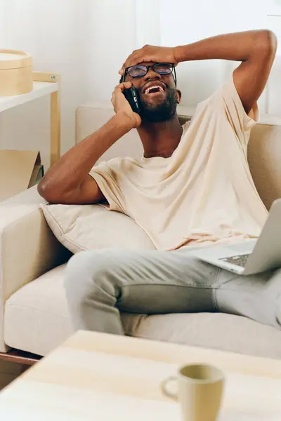 Усміхнений Афроамериканський Чоловік Використовує Ноутбук Телефон Вдома Інтернет Магазинів Комунікацій — стокове фото