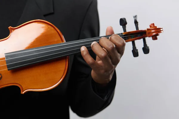 Closeup of a man in a black suit playing a violin on a white background, musical performance concept