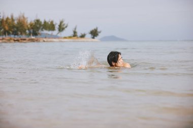 Aktif Asyalı Adam Serinletici Mavi Okyanus Suyu 'nda Tropikal Yüzüşün Tadını Çıkartıyor
