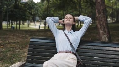 Elinde telefonla parkta ahşap bankta oturan bir kadın, dışarıda çalışıyor ve rahatlıyor, serbest çalışan bir hayat tarzı. Yüksek kalite 4k görüntü