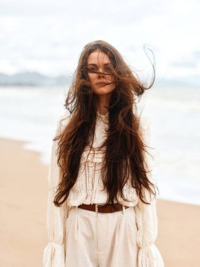 Sunny Summer Beauty: Moda Saçlı ve Güzel Elbiseli Genç Kadın, Mavi Okyanus kıyısındaki Tropikal Sahilde Rahatlıyor