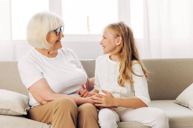 Kadın büyükanne yaşlı yaşam tarzını seviyor. Torun ailesine sarılıyor. Anne kız kanepeye bakıyor.