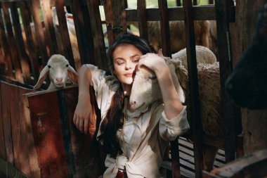 Çitin önünde kafası bir koyunun omzunda oturan bir kadın var.