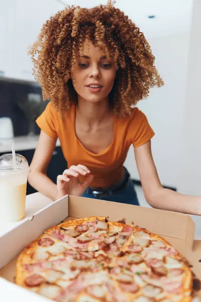 幸せな若いアフリカ系アメリカ人女性は 彼女の居心地の良い家庭のキッチンでランチのための美味しいピザを楽しんでいます — ストック写真