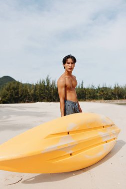 Mutlu Asyalı Adam Tropikal Sahilde Kano Macerasının tadını çıkarıyor