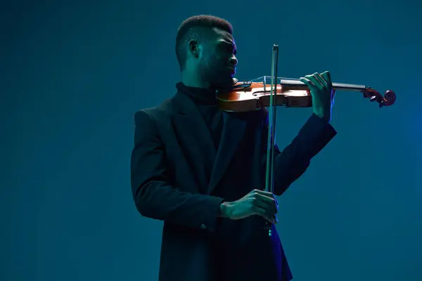 Eleganter Musiker Spielt Geige Schwarzen Anzug Vor Leuchtend Blauem Hintergrund — Stockfoto