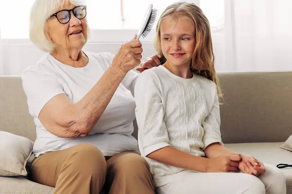 Woman couch senior girl hair sofa daughter happy elderly love grandmother old hug combing family comb lifestyle child mother granddaughter home hair