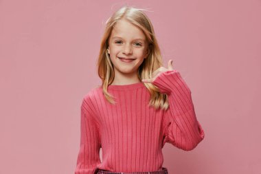 Stüdyoda gülümseyen Pembe Moda 'lı mutlu öğrenci yüzünde neşeli bir ifade olan güzel bir genç kız stüdyonun arka planında şık pembe bir elbiseyle duruyor.