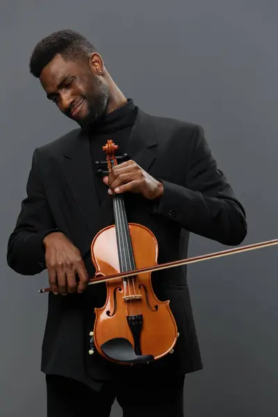 身穿黑色西服的非裔美国人 持有灰色背景的小提琴 音乐艺术和表演理念 — 图库照片