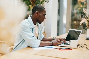 Siyahi, genç, çalışan bir iş adamı. Masa başı bilgisayar, afrika iş teknolojisi kullanıyor. Ofis işi, profesyonel laptop işi.