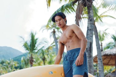 Serene Summer Kayak: Mutlu Asyalı Adam Tropikal Plajda Keyifli Kano Macerası Yapıyor