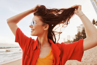 Ağzı açık gülümseyen kadın kumsalda gün batımının zevkini çıkarıyor.