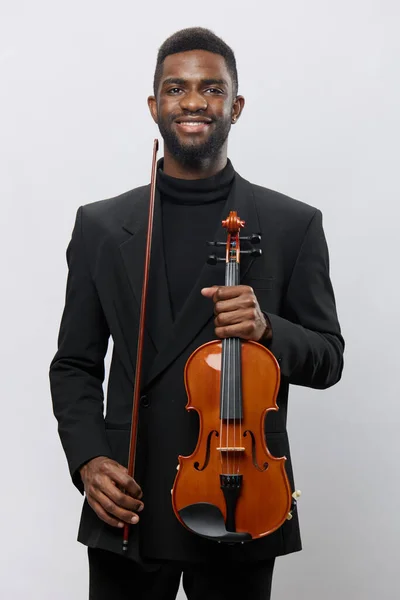 身穿黑色西服的文雅男子手持小提琴 对着相机微笑 以时尚的职业肖像画理念 — 图库照片