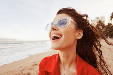 Renkli Günbatımı Kaçışı: Açık Ağzı ile Gülümseyen Bir Kadın, Sahilde Özgürlük ve Neşe Kucaklayan, Moda Kırmızı Giysilerle Dertsiz Tatilin Tadını Çıkaran